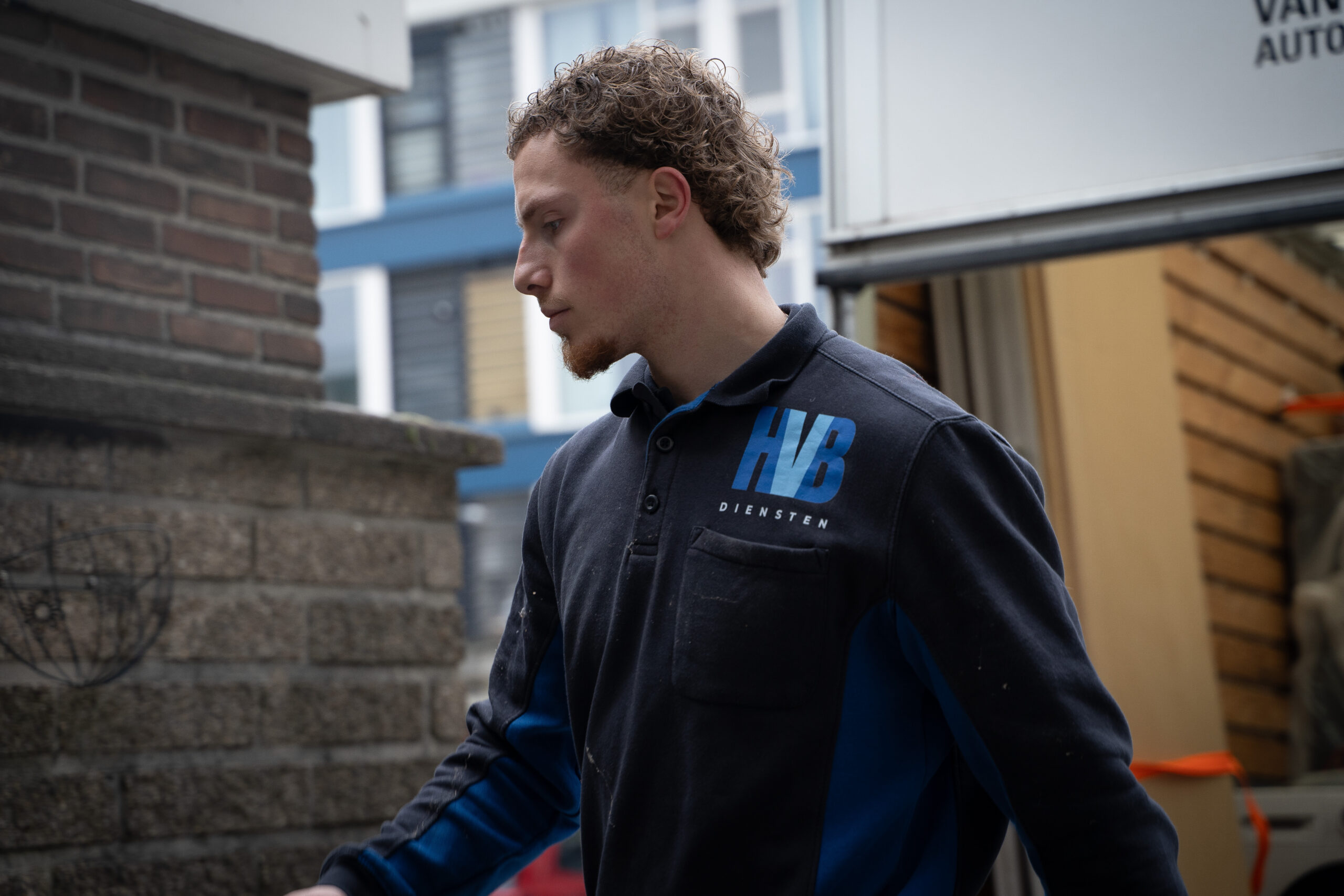 HVB-medewerker in blauwe polo aan het werk op een binnenplaats in Rotterdam